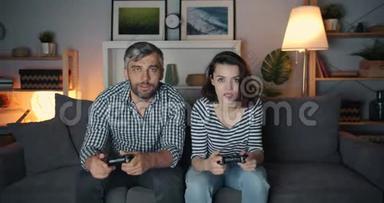 兴奋的男人和女人在黑暗的公寓玩电子游戏玩得开心